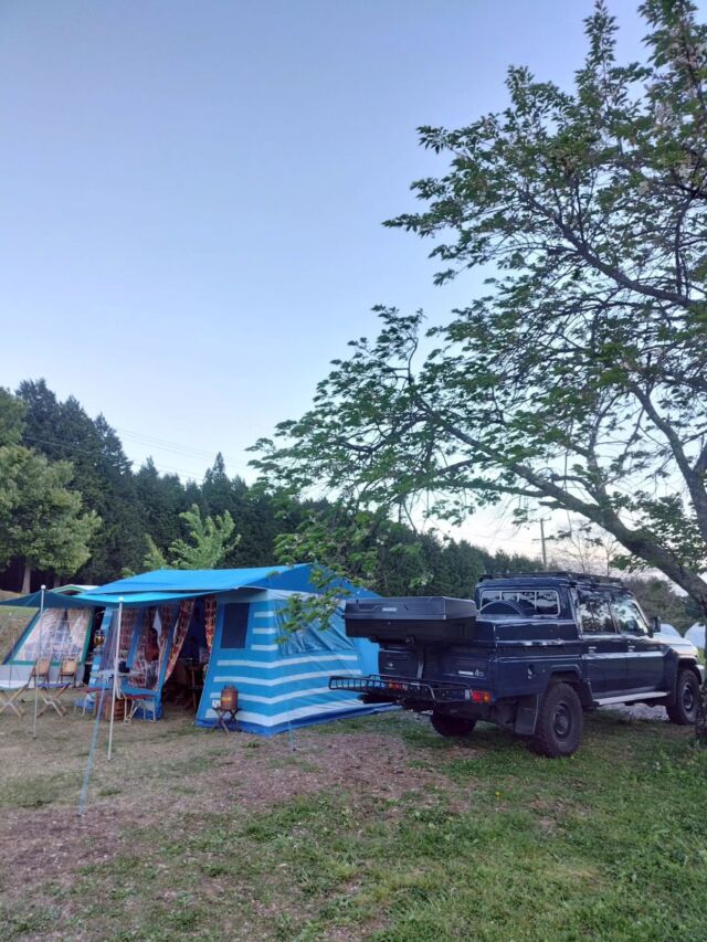 2026GWキャンプ  GWの野営地は、南信州飯島町の千人塚公園キャンプ場。
いつものメンバーとそして、関西や東海や関東や甲信越や東北の人たちと、楽しいキャンプ時間を過ごしてきました。  俺が今年のGWの行き先を決める前に「仲間を連れてお越しください。」と仙台の友から熱烈なオファーを受けたのは、年明け間もない頃でした。実は今年のGWには行きたいところがあって「まいったなぁ🤔予定を抑えられてしまった🙄」と正直なところ思ったのは、ココだけの話です🤣  初日の夜間に受けた暴風雨による被害、ロッジ型テントは暴風への備えは万全に取れたけれど、長時間の豪雨に対しては、ヴィンテージなコットン生地であったが故に(古ければ古いほど)無力で、水害はとても大きく、長いキャンプ人生の中でも記憶に残る苦い経験となりました。
一夜明け、オーニング下から見上げた青空に広がる、頂きに雪渓を残す中央アルプスの情景は、とても雄大でとても美しく、感動を覚えました。南アルプスと中央アルプスを生活の中で同時に望むことが出来る飯島町の豊かさを感じることが出来ました。  これまで数え切れないキャンプ場に訪れていますが、バランスの取れた本当に良いキャンプ場だと思います。欲を言えば陽射しを凌げる林間のファミリーサイトが充実していれば、100点満点💮💯かな。
厳しい自然の猛威に陥落しながらも、こんな風に感じるキャンプになったのは、キャンプ場のスタッフのみなさんの人柄、全国から集まりキャンプをご一緒いただいた皆さんと過ごした時間が心地良かったからだと思うのです。  仙台の友よ
俺の予定を早くから抑えてくれてありがとう😝  #2026GW #GRJ79 #ヴィンテージスタイルキャンプ #信州大好き #千人塚公園キャンプ場